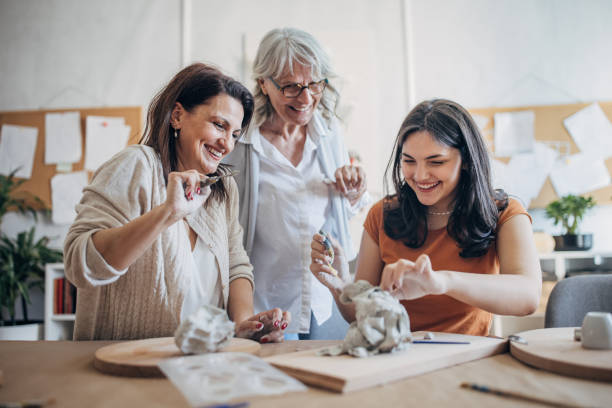istock Women molding clay together 1480096209