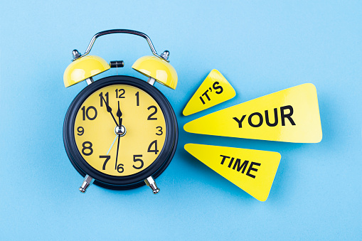 Alarm clock and text It's your time on blue background. The clocks time is showing 5 to 12.