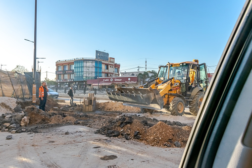 Cheraga, Algeria - December 18, 2022: Tunnel construction site in the national road RN 41 by day. Backhoe tractor excavator or bulldozer loader and active workers.