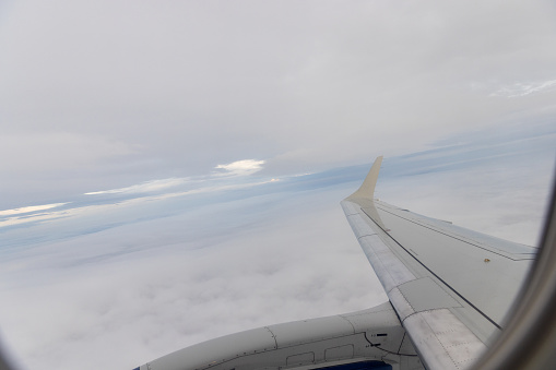 view of jet plane wing on the background of thick clouds and blue sky.