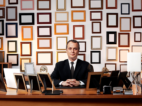 Businessman in office with lots of diplomas and picture frames