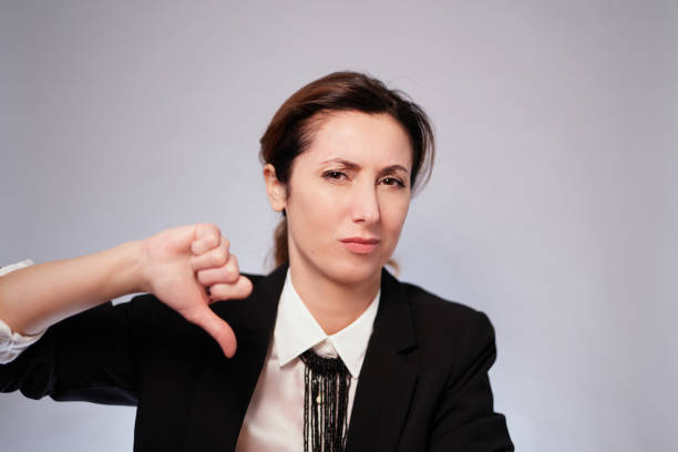 Negative emotion and gesture concept. Woman in black jacket posing on grey wall