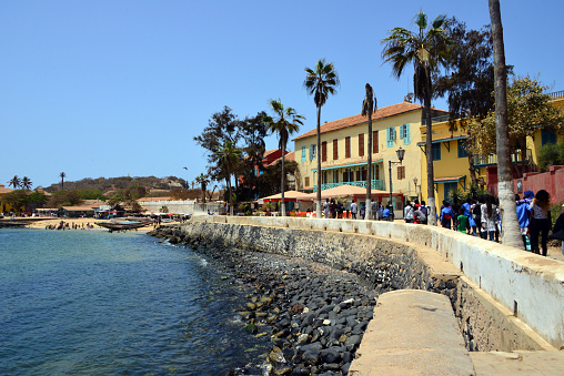 Island of Gorée, Dakar, Senegal: people along Hesse street, the corniche, near the post office, originally the Maurel Frères building (1822), the island's largest commercial enterprise. The beach can be seen on the left.
