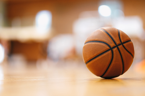 Imagen en primer plano de la pelota de baloncesto sobre el piso en el gimnasio. Pelota de baloncesto naranja sobre parquet de madera. photo