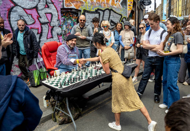 un desafío de juego de ajedrez que atrae a una gran multitud en brick lane market. una atracción turística popular en el east end. - 6727 fotografías e imágenes de stock