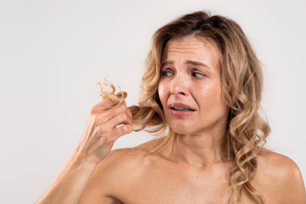 extremos secos. mujer estresada de mediana edad mirando su cabello dañado - bathtub women naked human face fotografías e imágenes de stock