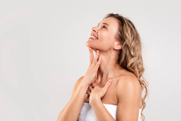 Double Chin Treatment. Beautiful Middle Aged Woman Touching Smooth Skin On Neck Double Chin Treatment. Beautiful Middle Aged Woman Touching Soft Smooth Skin On Neck, Attractive Mature Lady Standing Wrapped In Towel Over Light Grey Background, Enjoying Her Beauty, Copy Space chin stock pictures, royalty-free photos & images