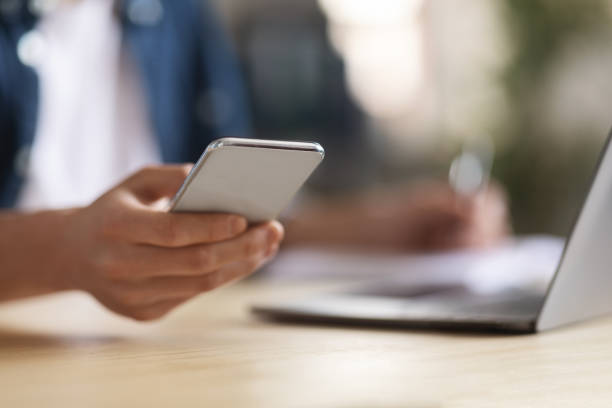 istock Young Male Using Modern Smartphone While Sitting At Desk With Laptop 1480107206
