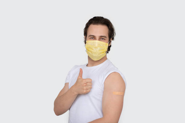 istock Smiling millennial caucasian man in protective mask show shoulder with band aid after immunization, thumb up 1480107285