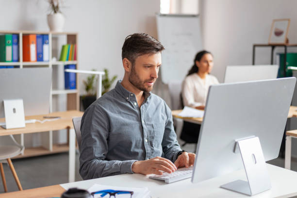 istock Busy handsome millennial european man manager typing at computer at workplace in modern office interior 1480107349