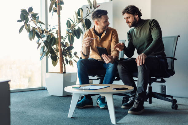 istock Male colleagues using tablet pc and talking, working on business project together, discussing ideas in modern office 1480107714
