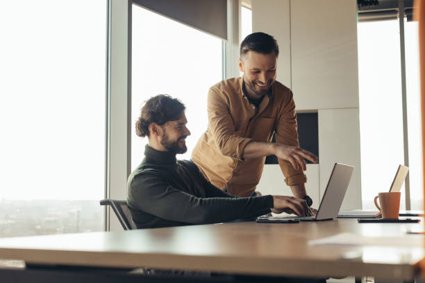 istock Positive male employees discussing business project, using laptop computer, brainstorming for ideas at modern office 1480107733