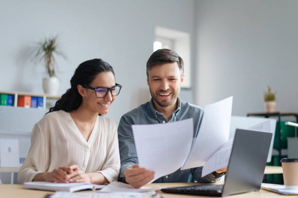 istock Cheerful male and female company workers looking through documents, collaborating, using laptop at modern office 1480107820