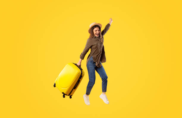 istock Joyful Traveler Lady With Suitcase Jumping Over Yellow Background 1480108122