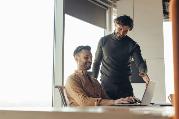istock Positive male colleagues discussing common project, using laptop, brainstorming for ideas at modern office, empty space 1480108224