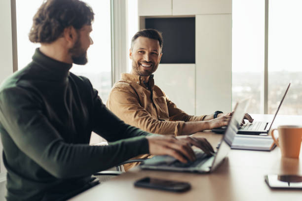 istock Cheerful company employees cooperating, working on common business project, using laptops at workplace 1480108243