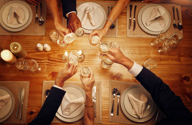 お祝い、大晦日、誕生日のディナーでのお祝いのためのシャンパン、グラス、歓声。レストランや自宅のダイニングテーブルで乾杯を祝うためのパーティー、イベント、ワインの上面図。 - 60 65 years ストックフォトと画像