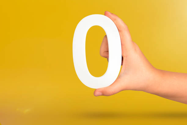 istock Numeral zero in hand. A hand holds a white number zero on a yellow background with copy space. Zero concept, 0 percent interest rate, minimum air emissions, cost or credit no increase. 1480114030