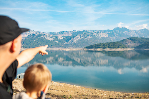 Father showing fish farm at mountain lake to his little son