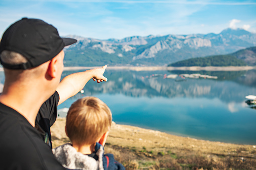 Father showing fish farm at mountain lake to his little son