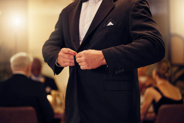Suit, formal and man tie the button of his jacket at a fancy dinner, party or event banquet. Classy, elegance and male fixing blazer of his elegant outfit at classic supper, celebration or gathering. Suit, formal and man tie the button of his jacket at a fancy dinner, party or event banquet. Classy, elegance and male fixing blazer of his elegant outfit at classic supper, celebration or gathering. dinner jacket stock pictures, royalty-free photos & images