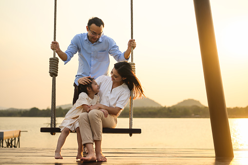 Family enjoying with outdoor activities sitting on swing with sunset on vacation, Happy family father mother and children enjoying picnic at park, Family with happy lifestyle
