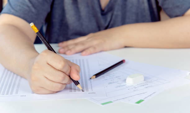 istock Students hand holding pencil writing selected choice on answer sheets and Mathematics question sheets. students testing doing examination. school exam 1480121661