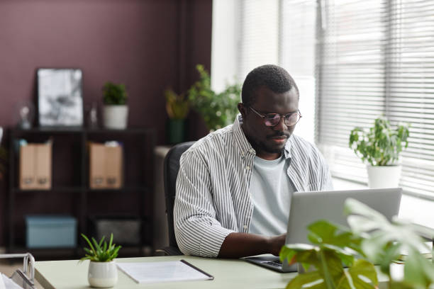 istock Black businessman using laptop at home office workplace with green plants 1480122943