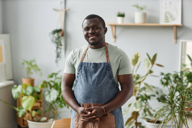 istock Smiling black man as gardener wearing apron posing indoors looking at camera 1480122984