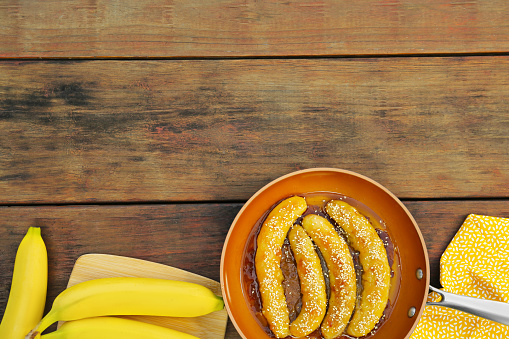 Delicious fresh and fried bananas on wooden table, flat lay. Space for text