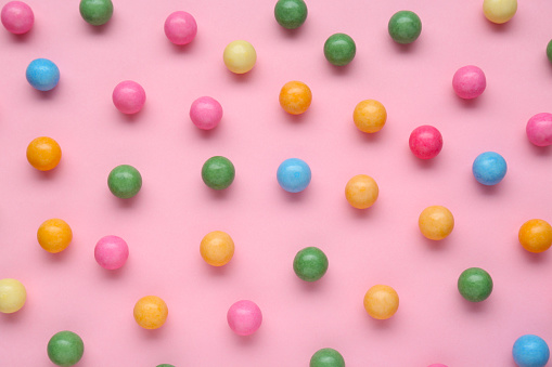 Many bright chewy gumballs on pink background, flat lay