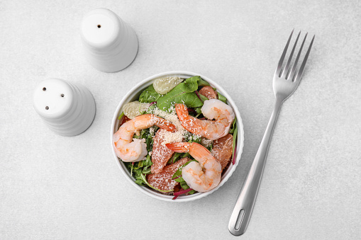 Delicious salad with pomelo, shrimps and tomatoes on white table, flat lay