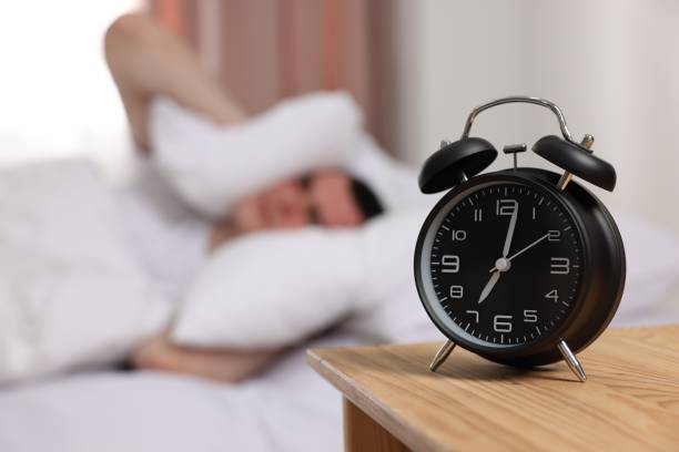 istock Man covering his ears with pillows in bedroom, focus on alarm clock. Space for text 1480126863