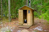 Wooden outdoor toilet in the forest with an open door. toilet paper roll.