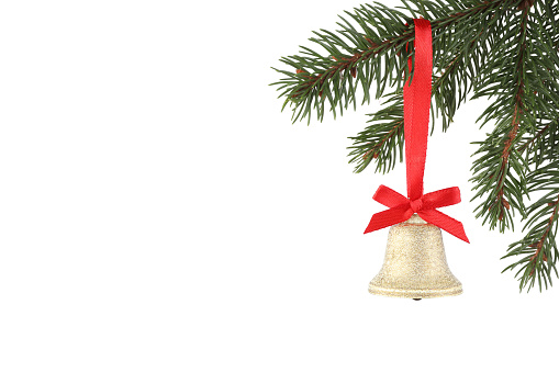 Christmas bell with red bow hanging on fir tree branch against white background