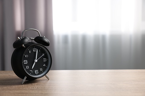 Black alarm clock on wooden table indoors, space for text