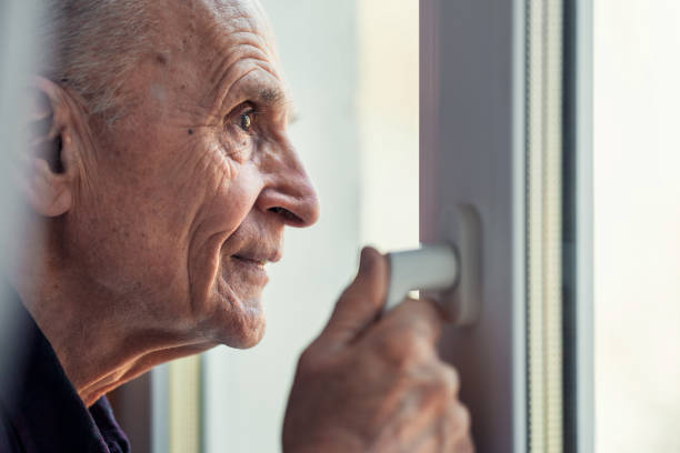 istock Pensive look of elderly person who looking through window frame 1480128582