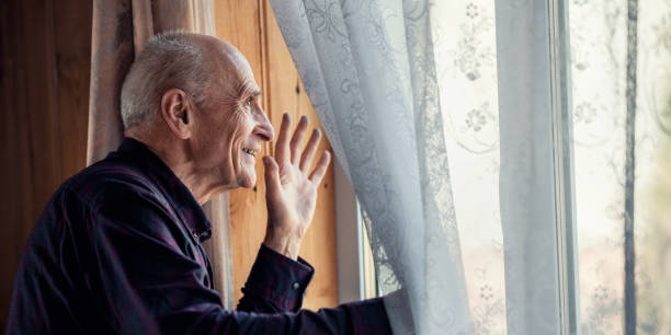 istock Smiling senior man wearing simple shirt waving with hand through window 1480128698