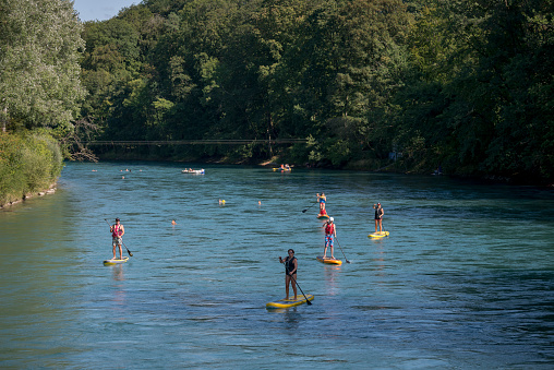 Bern, Switzerland - August 15, 2018: On a beautiful summer day paddleboarders travel down the Aare River in Bern, Switzerland.