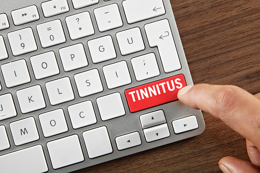 Man pushing ”Tinnitus” key on computer keyboard.