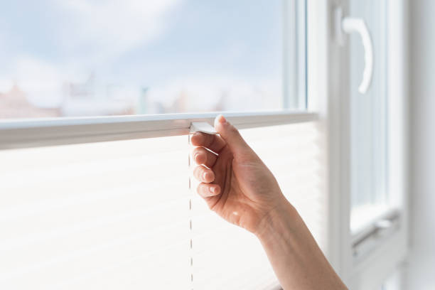 mujer abre persiana inalámbrica persiana en la ventana - blinds showcase interior home decorating window fotografías e imágenes de stock