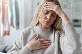 unhealthy woman in fever touching forehead and chest