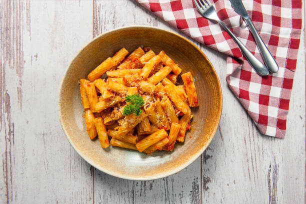 vista superior de la pasta rigatoni con salsa arrabiata sobre una mesa de madera blanca - rigatoni fotografías e imágenes de stock