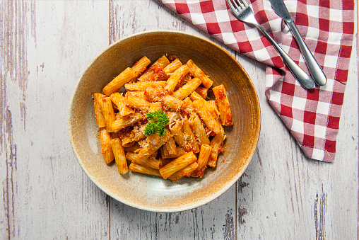 Top view of delicious looking rigatoni pasta with arrabiata sauce on a white wooden table