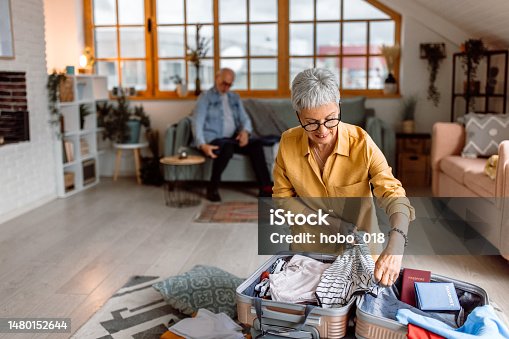 istock Senior woman packing suitcase, preparing for vacation trip 1480152644