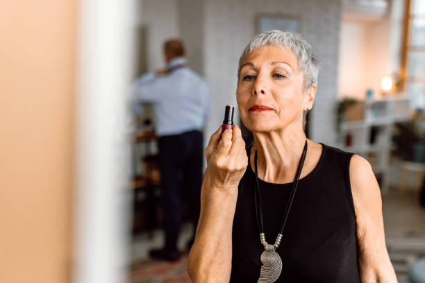 Senior woman applying a lipstick wile looking in a mirror