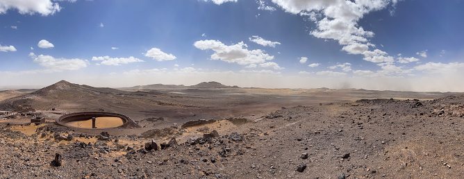 Merzouga, Morocco, Africa: panoramic view in the Sahara desert at the fossil mines in the Black Mountain area, blue sky and white clouds