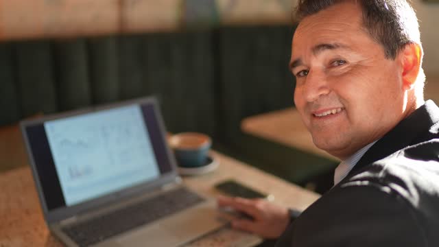 Portrait of mature businessman using laptop at a coffee shop