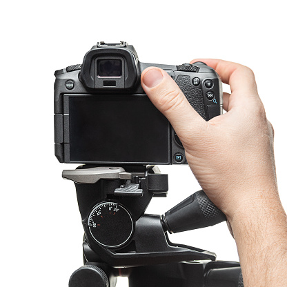 Hand and camera on tripod on white background