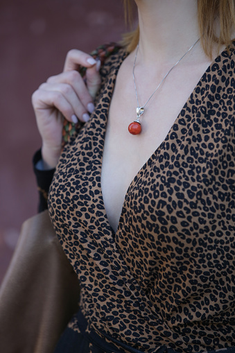 Close up of V neck leopard print shirt and silver necklace with orange gemstone goldstone crystal pendant